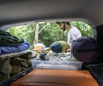 Man getting camping gear from vehicle.